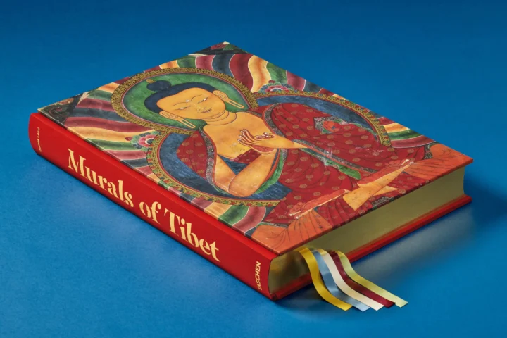 The “Murals of Tibet. BABY SUMO” hardcover on a blue background, with a painted figure on the cover and coloured ribbon bookmarks.